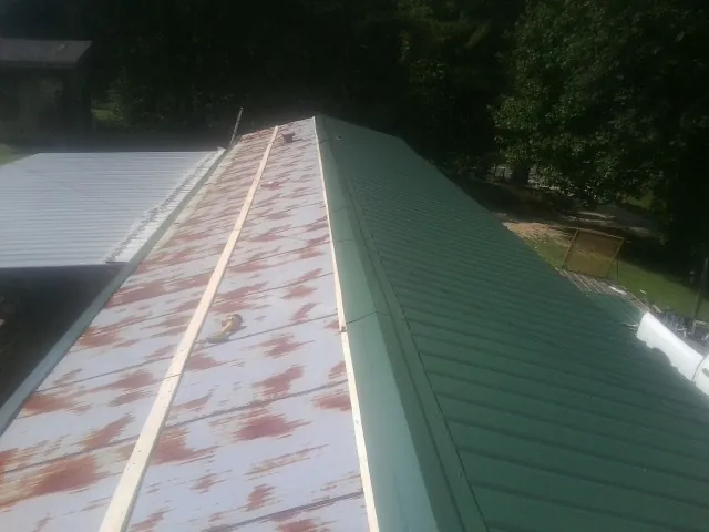 Old rusted panels beside newly installed green metal roofing — Wind Damage Roof Repair by Roofing Brothers in Ambridge