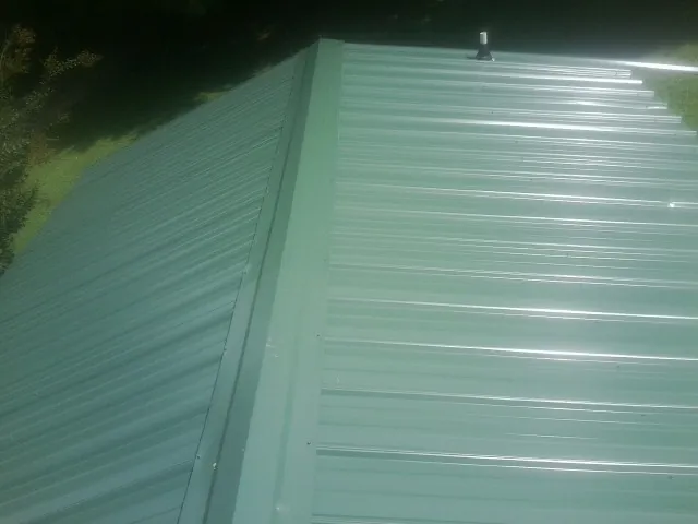 New green metal panels meeting at the ridge of a roof — Flat Roof Repair work by our crew in Ambridge