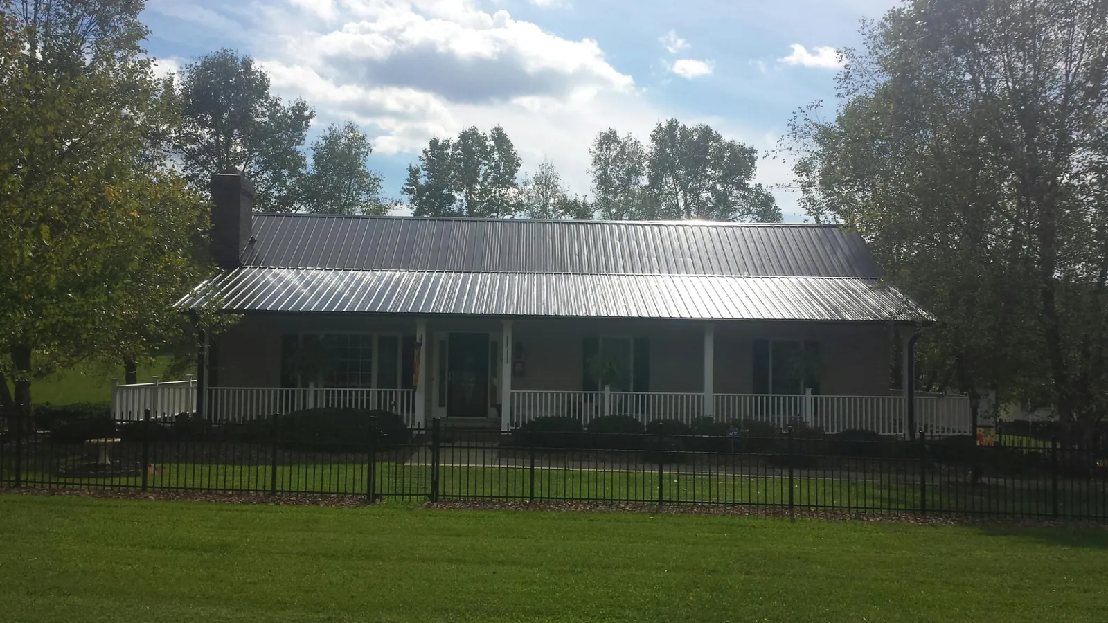 Gray metal roof on a brick ranch with a full width front porch — Gutter Guard Installation work by our crew in Ambridge