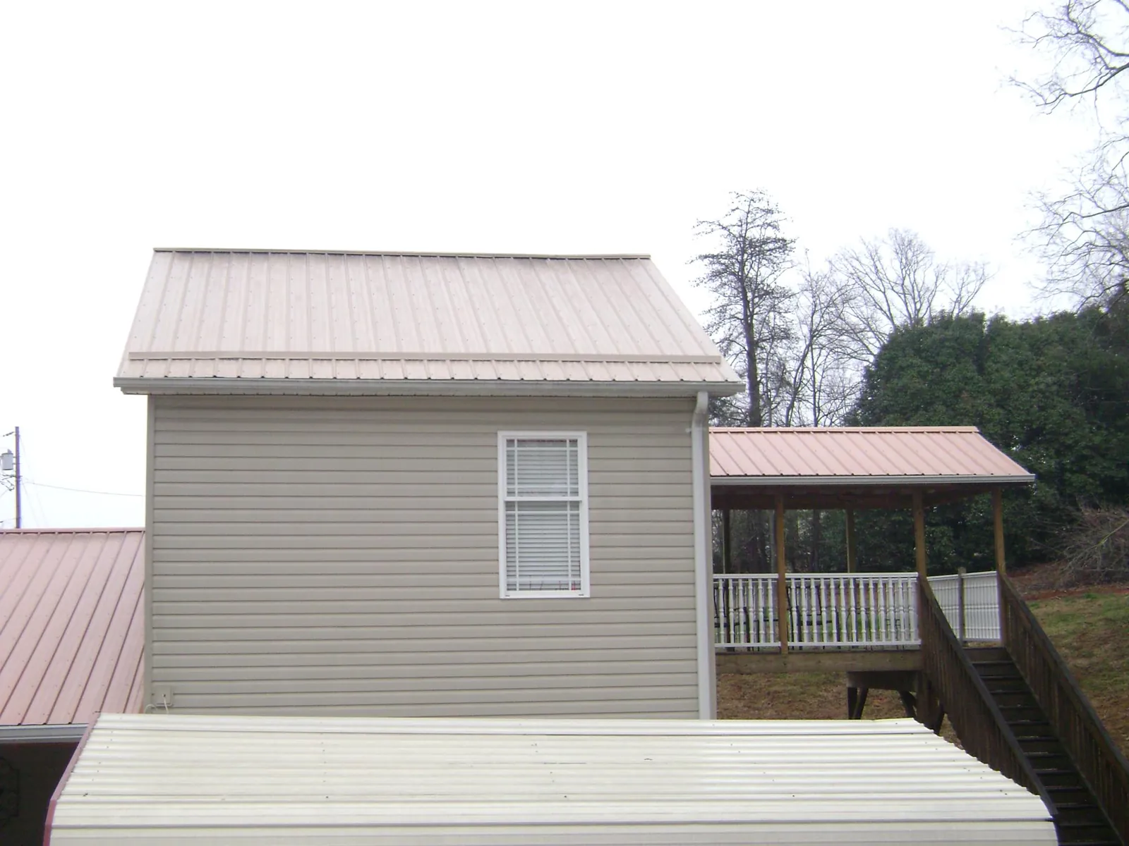 Tan metal roofs on a two story addition and attached porch, from a Roof Replacement job in Ambridge