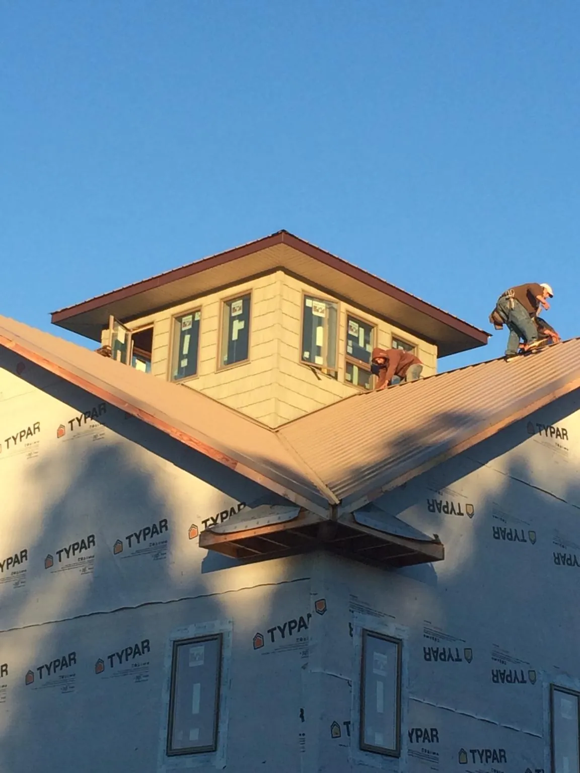 Roofers working around a rooftop cupola on a new metal roof at sunset — Roof Waterproofing in Ambridge by Roofing Brothers